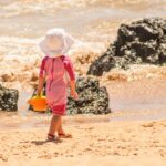 a little boy that is standing in the sand on a beach