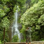 a man standing next to a waterfall