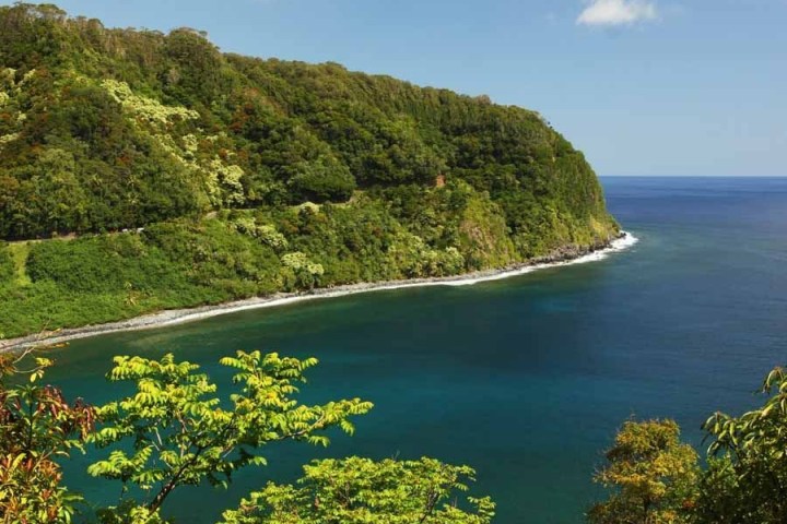 a body of water surrounded by trees with Hana Highway in the background